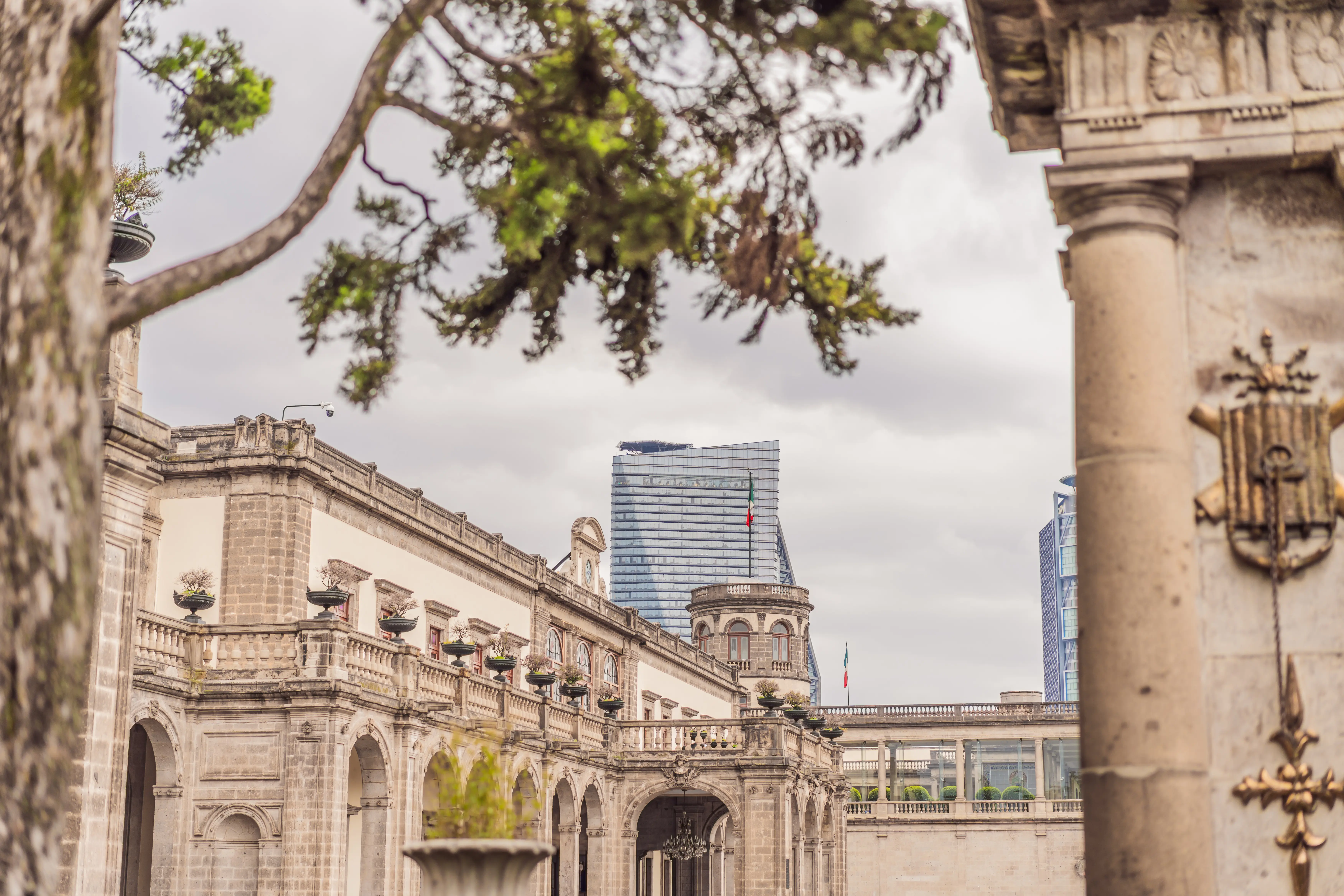 Chapultepec Castle courtyard framed by trees, with the Torre Reforma skyline beyond