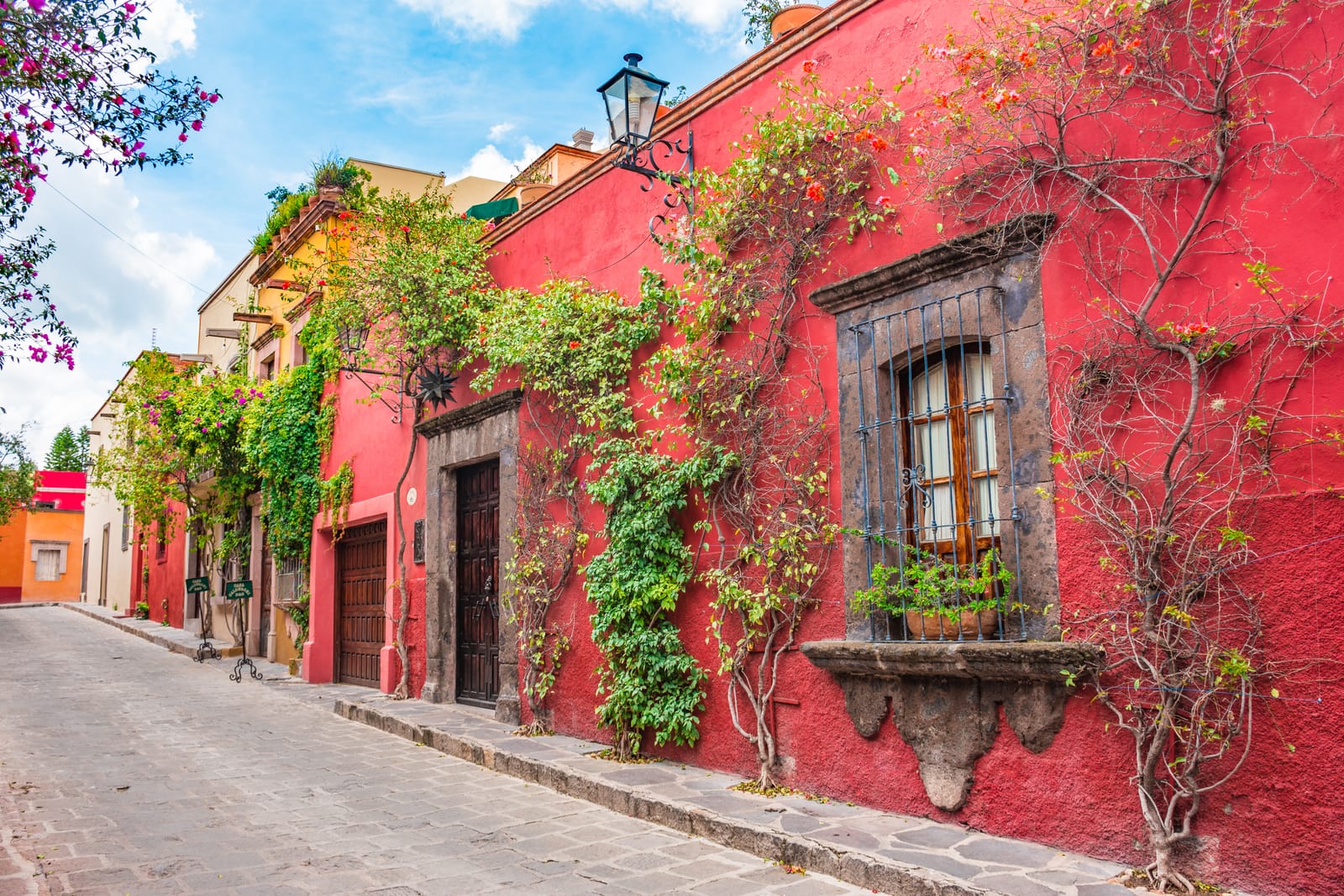 Red colonial house with climbing vines on a cobblestone street