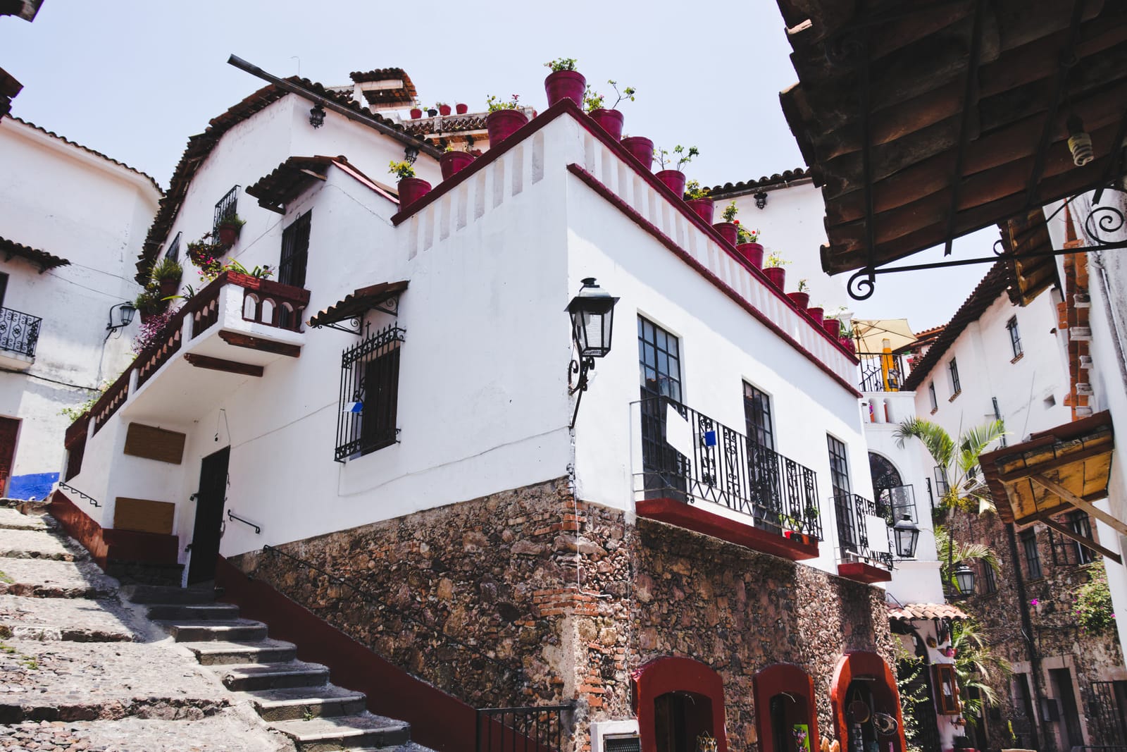 Whitewashed houses with red trim and iron balconies on a steep Taxco street