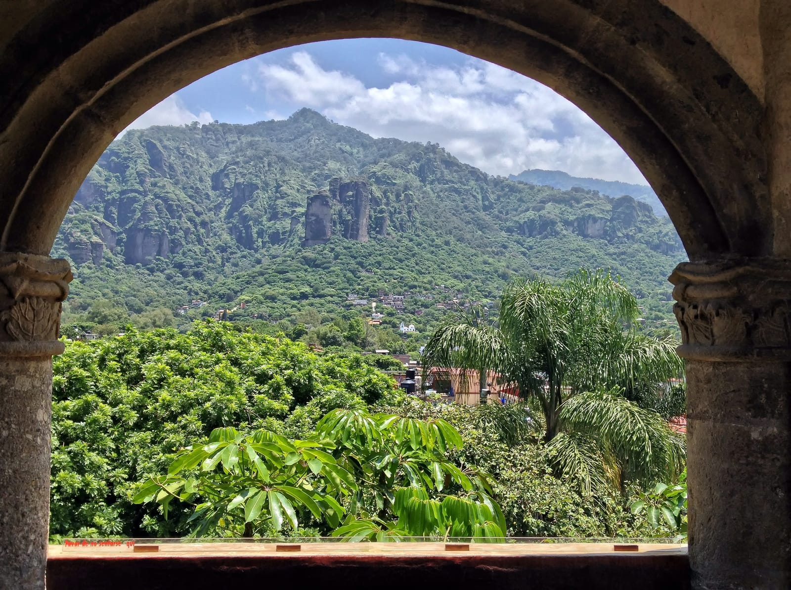 Green cliffs of the Tepozteco range seen through a stone arch
